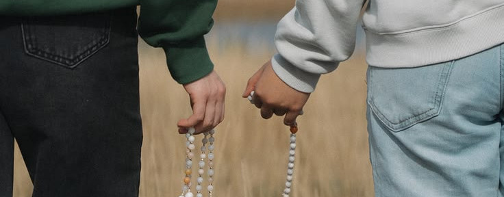 Two people holding rosaries